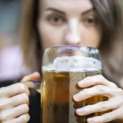 Kobieta pije piwo z dużego kufla. Czy wiesz, że dekstryna co to jest, może być składnikiem piwa?