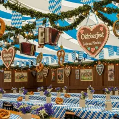 Wielkie precle, akordeony i serca z napisem "Oktoberfest Gruß aus München" wiszą pod niebiesko-białymi girlandami. Stoły przykryte są kratkowanymi obrusami, gotowe na świętowanie.