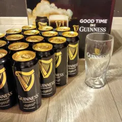 Dużo puszek Guinness z złotymi wieczkami i pustą szklanką, gotowe na dobrą zabawę z Guinness.