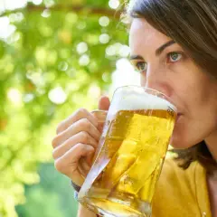 Kobieta popija orzeźwiające piwo lekkie w upalny dzień, ciesząc się chwilą relaksu wśród zieleni.