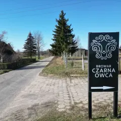 Znak kierunkowy do Browaru Czarna Owca. Stylizowana głowa owcy i strzałka wskazują drogę do tego miejsca.