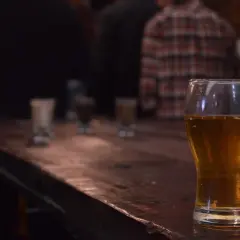Zimne IPA na drewnianym blacie, w tle ludzie. Idealne na wieczór.