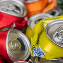 Stos zgniecionych puszek aluminiowych, czerwonych, żółtych i pomarańczowych, gotowych do recyklingu.