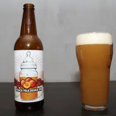 Butelka i szklanka z brzoskwiniowym milkshake IPA. Etykieta przedstawia butelkę z smoczkiem i brzoskwiniami.