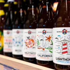 Rząd butelek piwa z etykietami Browar Brodacz. Na pierwszej widocznej etykiecie stylizowana latarnia morska i napis "Lighthouse".