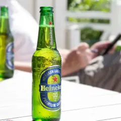 Chłodna butelka Heineken 0.0% na stole. Idealna na upalny dzień, gdy zastanawiasz się, heineken ile procent ma ten napój.