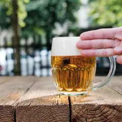 Dłoń dotyka gęstej piany na kuflu piwa, pokazując, jak powstaje piana.