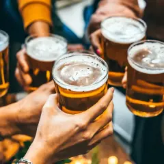 Przyjaciele wznoszą toasty piwem z browaru Koreb. Złocisty trunek w szklankach, piana i radosna atmosfera.