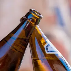 Dwie butelki z alkoholem w zielonej butelce zbliżają się do toastu.