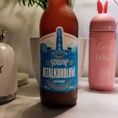 Piwo bezalkoholowe o smaku piwa, z etykietą latarni morskiej. Obok różowy kubek "Cute Rabbit" i lampka w kształcie głowy renifera.