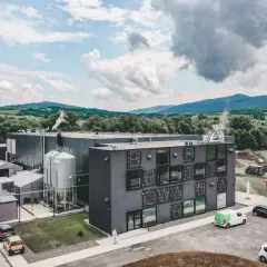 Nowoczesny browar Pinta, z charakterystycznym napisem na fasadzie, w malowniczej dolinie.