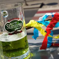 Szklanka zielonego piwa czeskiego Starobrno obok wierzbowej rózgi z kolorowymi wstążkami.
