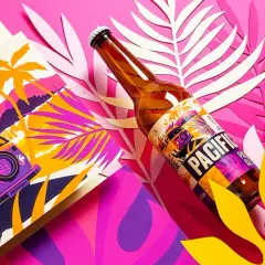 Butelka piwa Pacific z etykietą w stylu retro, obok grafiki z kamperem i palmami. To idealny towarzysz podróży od browaru artezan.