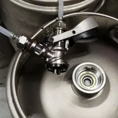 Metalowe kegi z piwem, gotowe do podłączenia. Widoczny kranik i wężyk, zapowiadające degustację.
