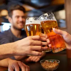 Trzech przyjaciół wznosi toast piwem, zastanawiając się, czy piwo to alkohol.