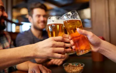 Trzech przyjaciół wznosi toast piwem, zastanawiając się, czy piwo to alkohol.