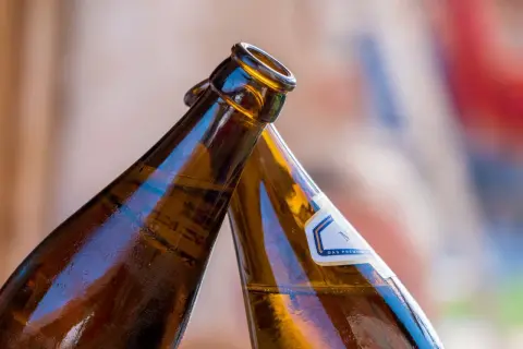 Dwie butelki z alkoholem w zielonej butelce zbliżają się do toastu.