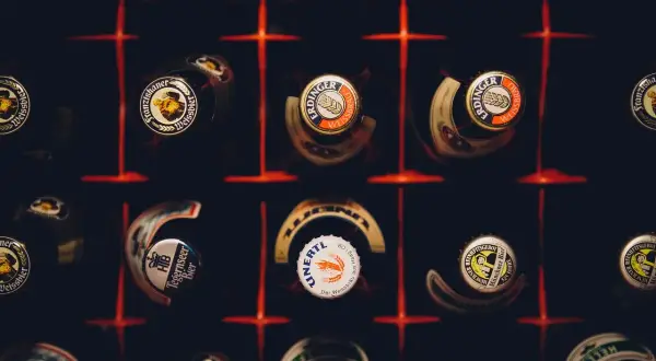 Kapsle piwne różnych marek, w tym Erdinger i Franziskaner, tworzą mozaikę. Każda kapsla to mały patron piwa, opowiadający historię smaku.