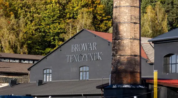 Browar Tenczynek, z charakterystycznym kominem i jesiennymi drzewami w tle. Właściciel dba o tradycję.