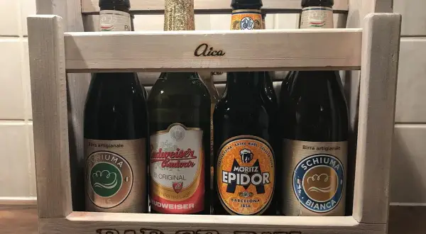 Drewniana skrzynka z piwami. Na pierwszym planie piwo w zielonej puszce, obok inne butelki. Na skrzynce napis "BAD CR PAH".