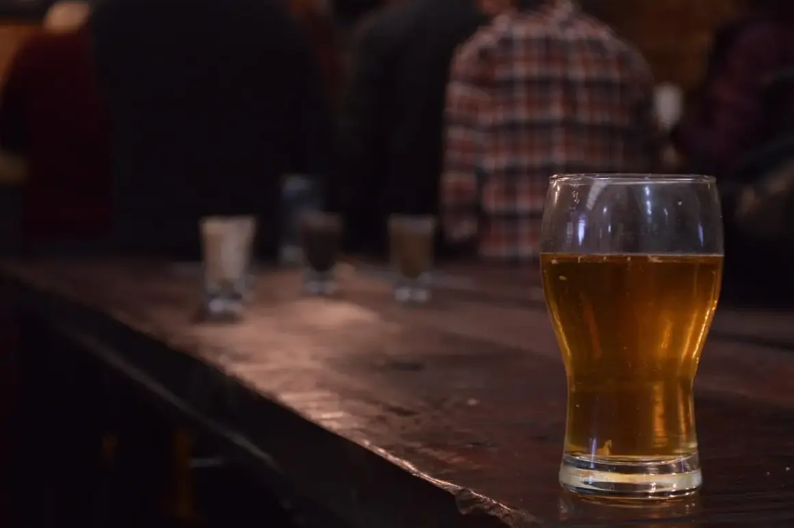 Zimne IPA na drewnianym blacie, w tle ludzie. Idealne na wieczór.