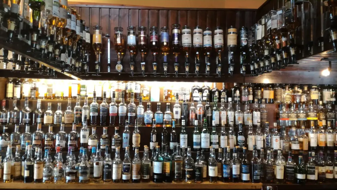 Wielka półka pełna butelek szkockiego piwa i whisky, gotowych do degustacji.