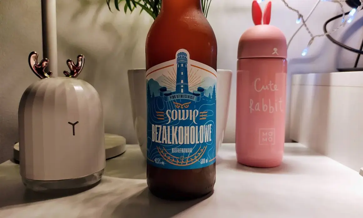 Piwo bezalkoholowe o smaku piwa, z etykietą latarni morskiej. Obok różowy kubek "Cute Rabbit" i lampka w kształcie głowy renifera.