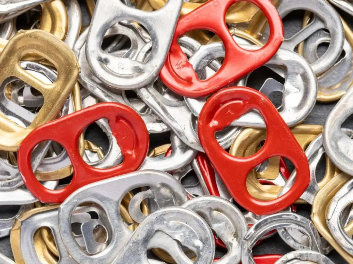 Mnóstwo srebrnych, złotych i czerwonych zawleczek od puszek tworzy barwną mozaikę. Co oznaczają zawleczki od puszek? To symbol recyklingu i możliwości tworzenia z nich czegoś nowego.