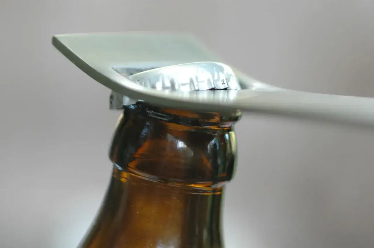 Metalowy otwieracz do piwa w akcji, gotowy do otwarcia butelki. Prosty sposób, jak otworzyć piwo.
