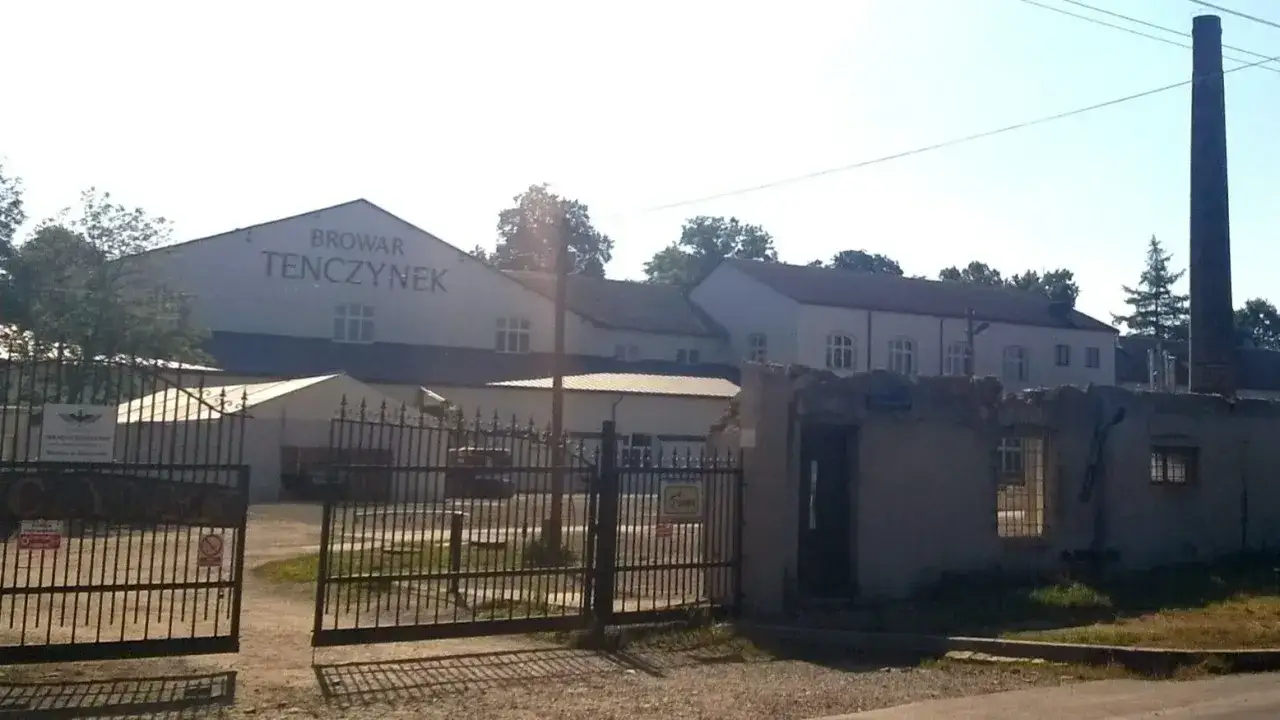 Browar Tenczynek, dawniej własność rodziny, dziś zaprasza do zwiedzania. Widać bramę, budynki i komin.