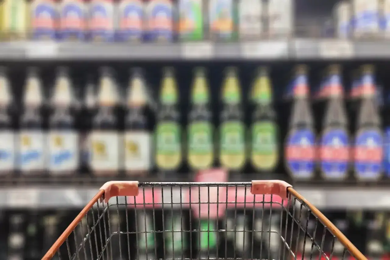 W&oacute;zek sklepowy przed p&oacute;łką z butelkami piwa. Szukam nowych kraftowych smak&oacute;w.