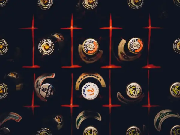 Kapsle piwne różnych marek, w tym Erdinger i Franziskaner, tworzą mozaikę. Każda kapsla to mały patron piwa, opowiadający historię smaku.