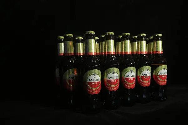 Rząd butelek piwa Amstel, kultowe piwo, w ciemnym otoczeniu.