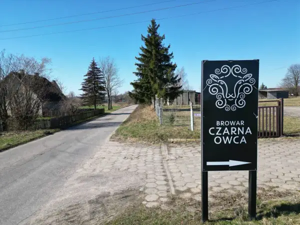 Znak kierunkowy do Browaru Czarna Owca. Stylizowana głowa owcy i strzałka wskazują drogę do tego miejsca.