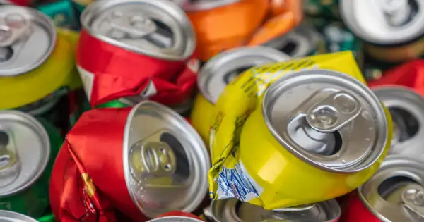 Stos zgniecionych puszek aluminiowych, czerwonych, żółtych i pomarańczowych, gotowych do recyklingu.