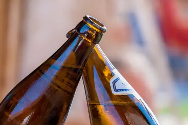 Dwie butelki z alkoholem w zielonej butelce zbliżają się do toastu.